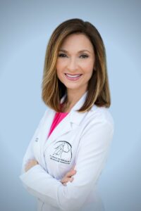 Photo of Dr. Lisa Radosta wearing a white lab coat with the logo of her business, Florida Veterinary Behavior Service.r