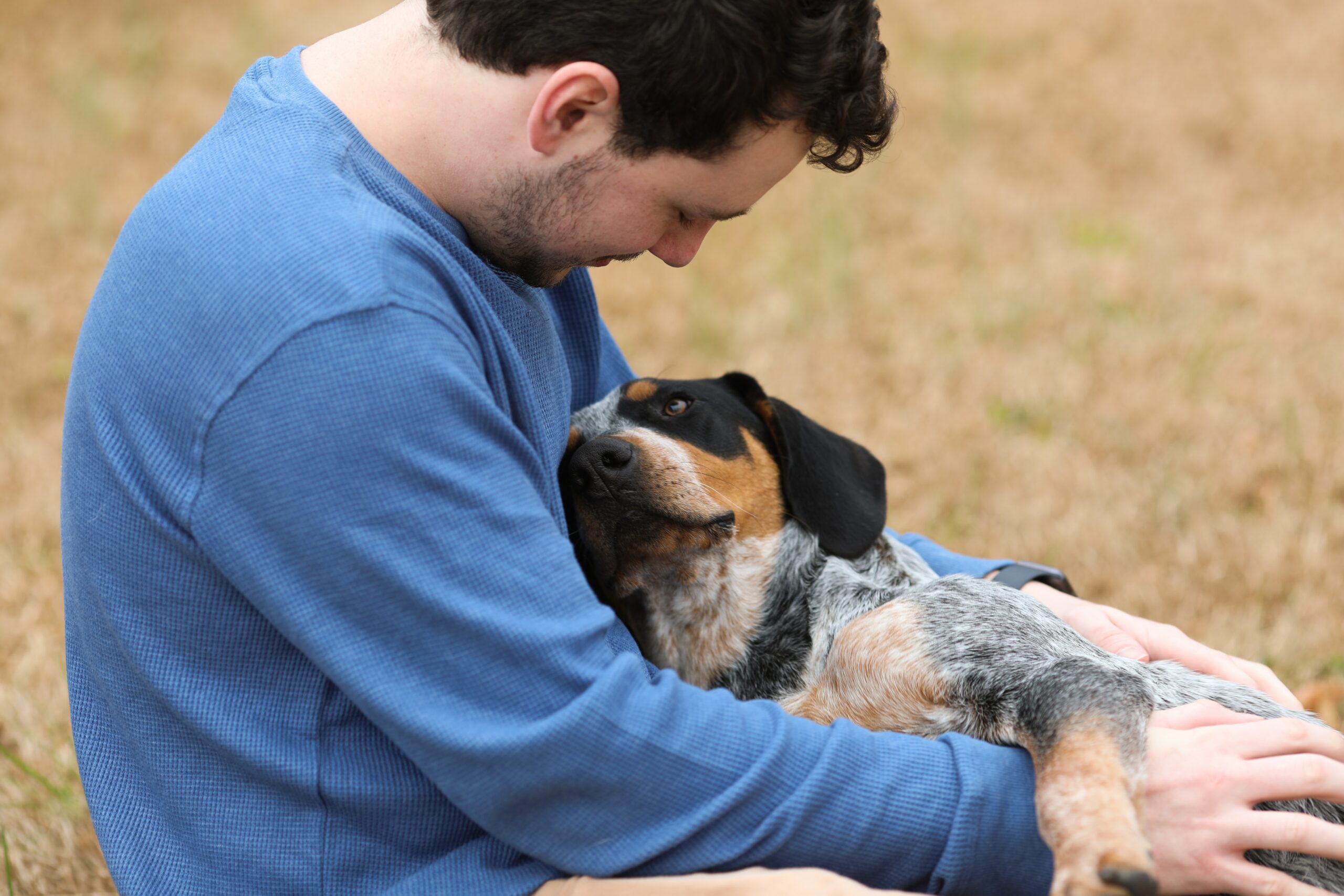 Man sitting with a dog in his lap looking up at him sweetly