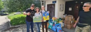 3 volunteers holding donations of pet supplies