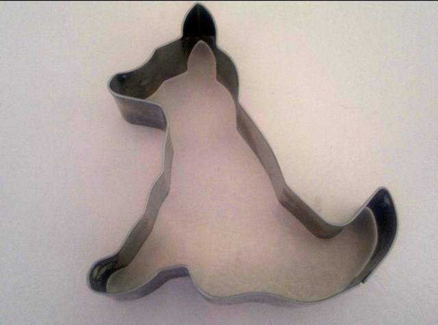 Cookie cutter in the shape of a dog. The dog is seated.