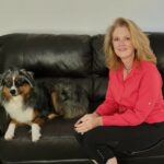 Author Niki Tudge, and her dog Doogie, sitting on a couch.