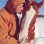 A man kissing a horse's face