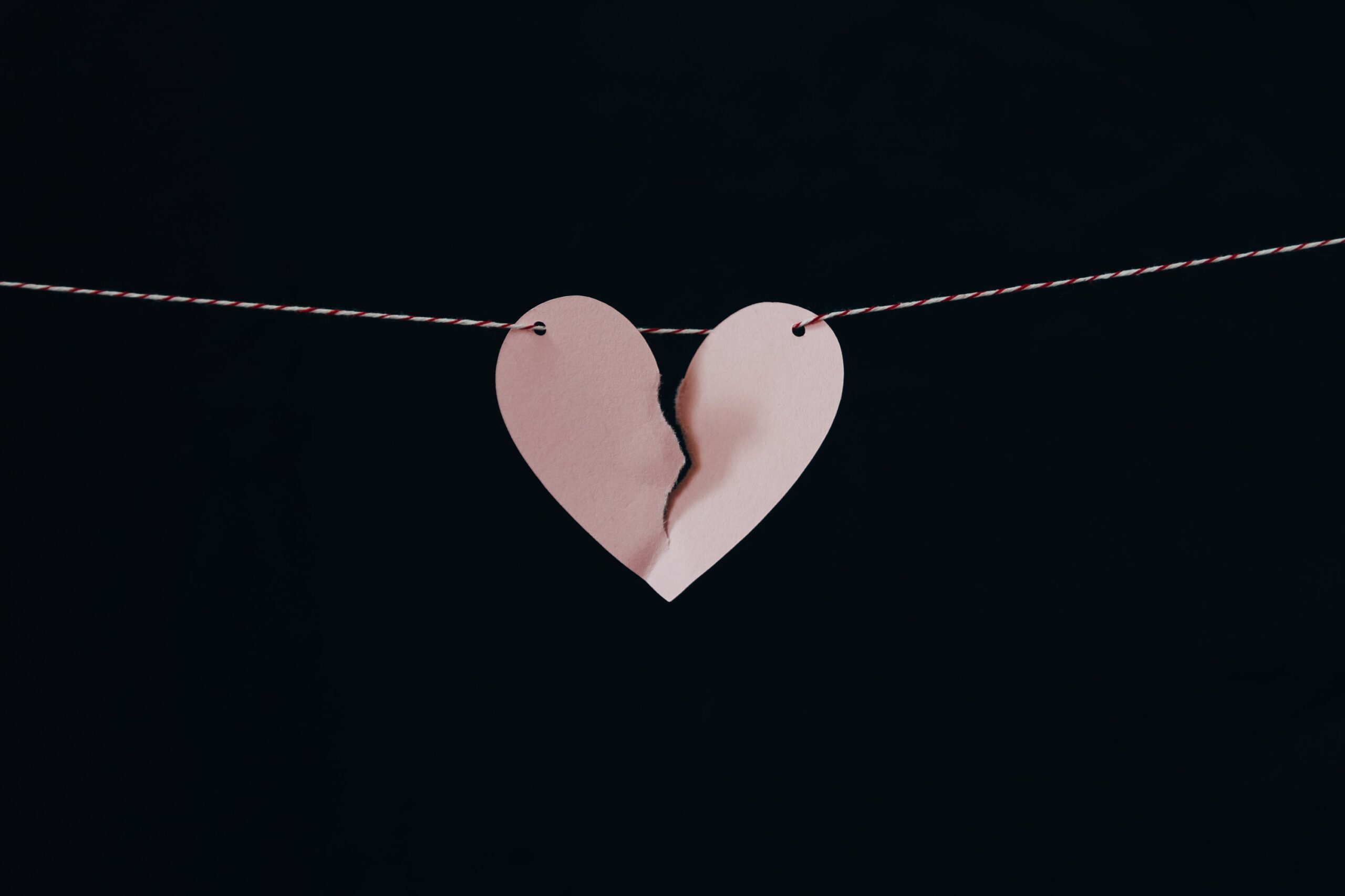 A torn paper heart suspended by a string