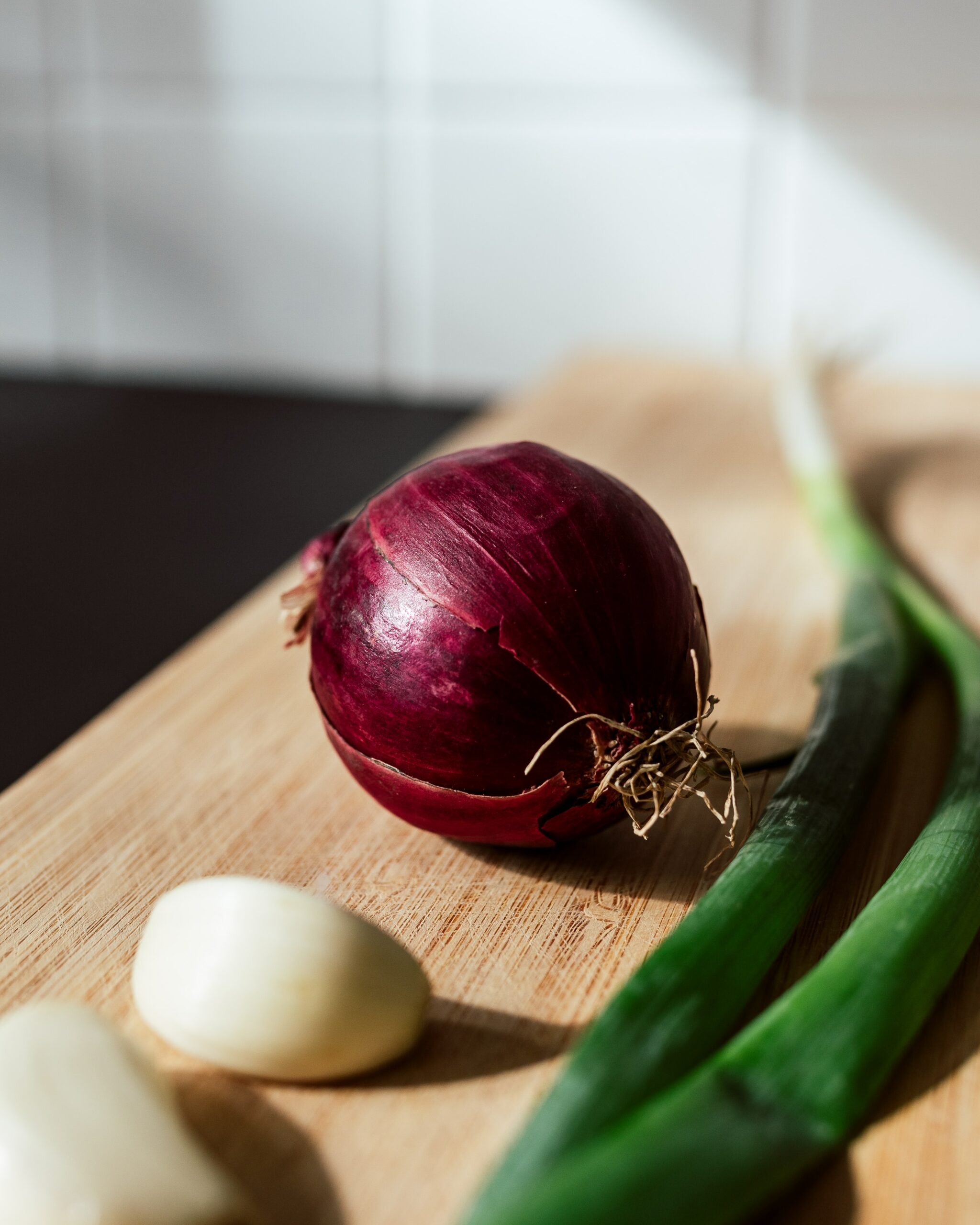 Onion, garlic, and scallions on a counter.